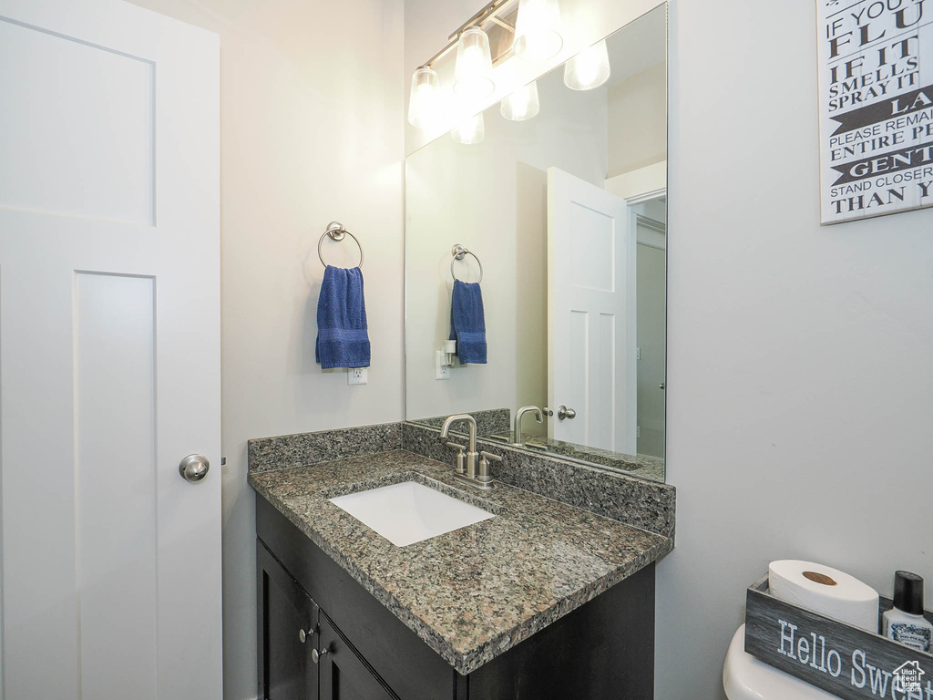 Bathroom featuring vanity with extensive cabinet space and toilet