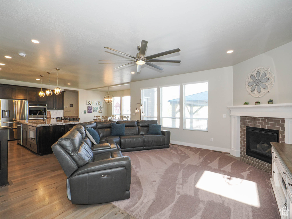 Living room featuring ceiling fan, hardwood / wood-style flooring, and a fireplace