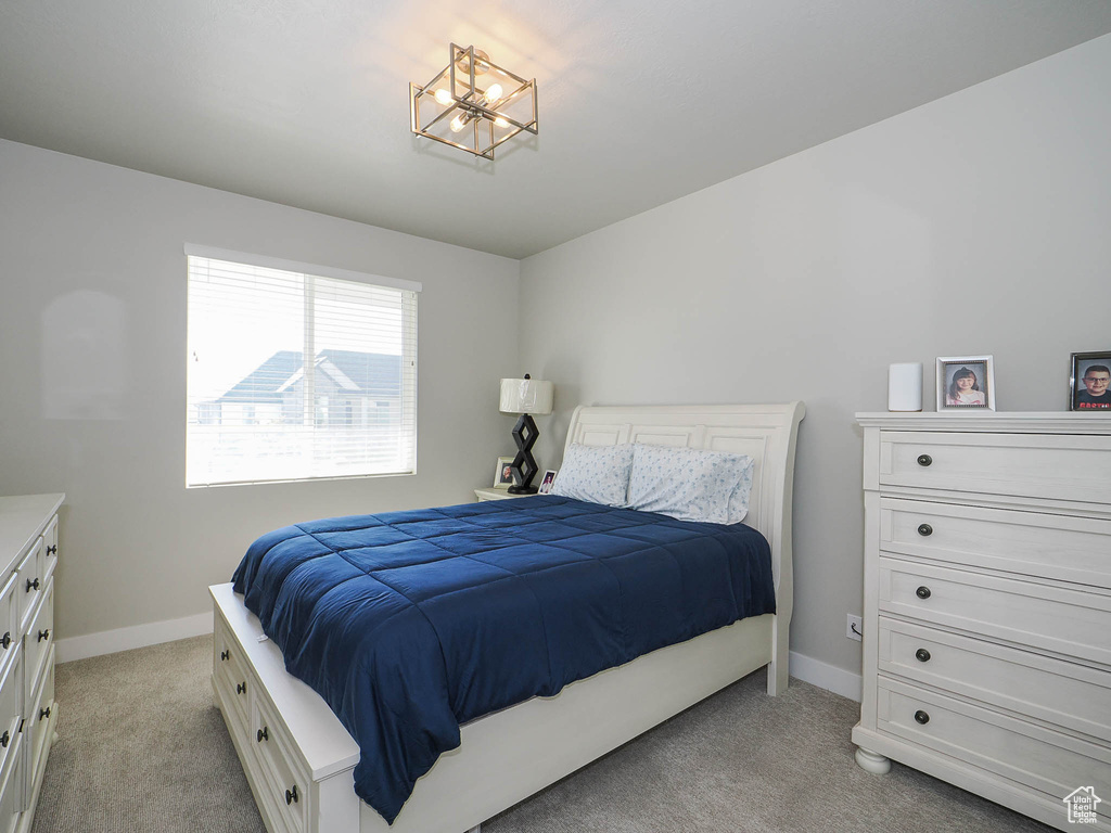 Bedroom with a notable chandelier and light colored carpet