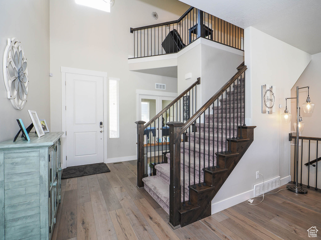 Entrance foyer featuring a towering ceiling and hardwood / wood-style flooring