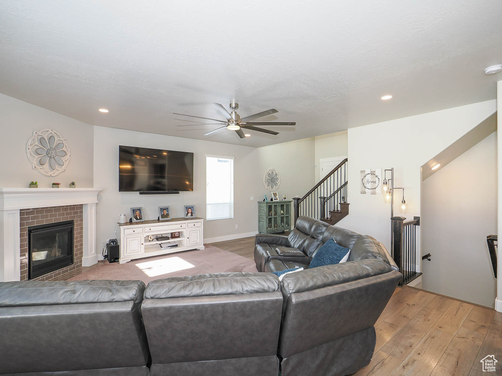 Living room featuring a brick fireplace, ceiling fan, and light wood-type flooring