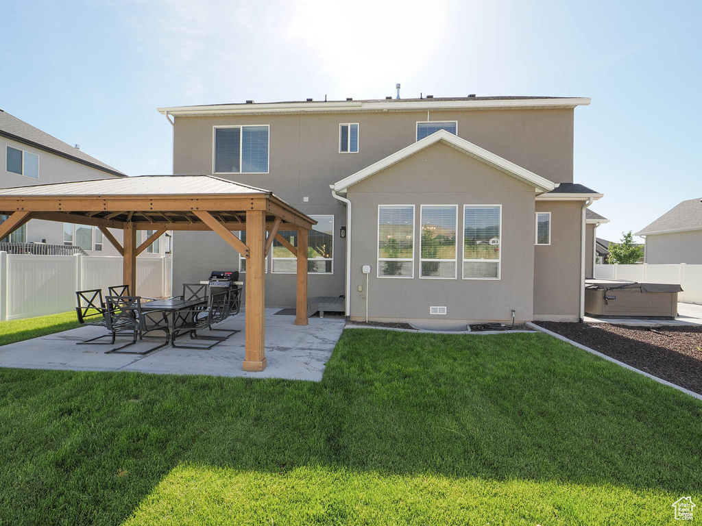 Rear view of property with a patio, a hot tub, a gazebo, and a lawn