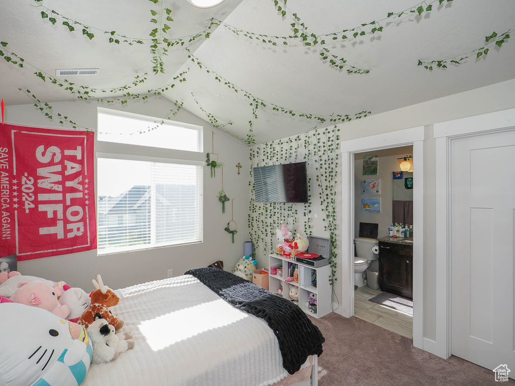 Bedroom featuring carpet, ensuite bathroom, and lofted ceiling