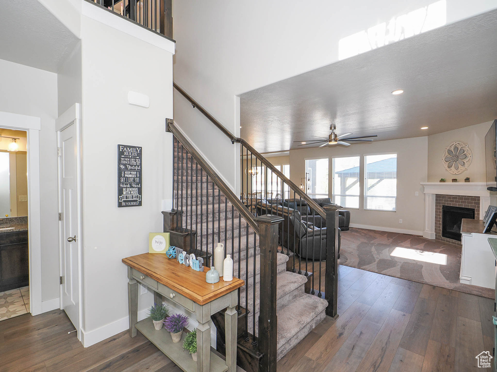 Staircase featuring ceiling fan, dark hardwood / wood-style floors, and a fireplace