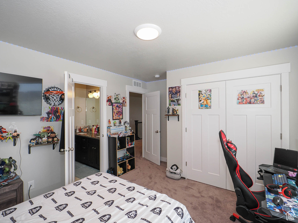 Bedroom with a closet, connected bathroom, and light colored carpet