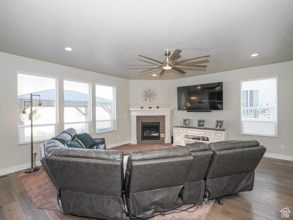 Living room featuring hardwood / wood-style floors, ceiling fan, and a fireplace