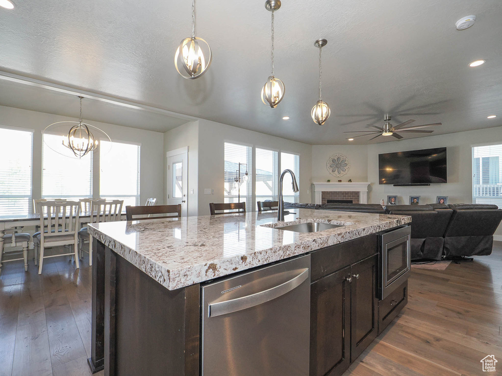 Kitchen featuring stainless steel appliances, a kitchen island with sink, sink, and dark wood-type flooring