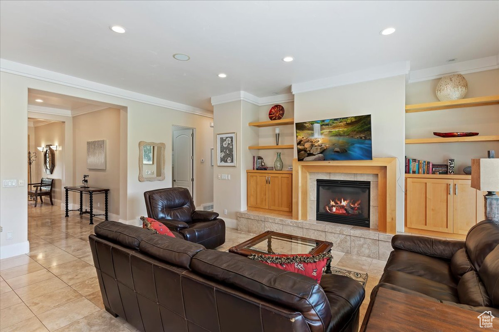 Tiled living room featuring built in features, ornamental molding, and a fireplace