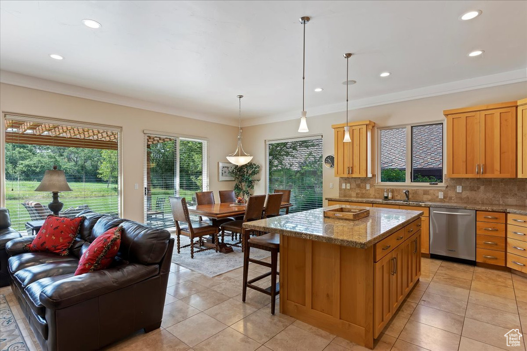 Kitchen with a center island, stainless steel dishwasher, decorative light fixtures, backsplash, and light tile flooring