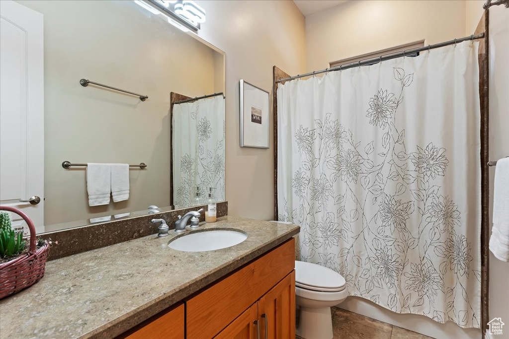 Bathroom with tile flooring, vanity with extensive cabinet space, and toilet