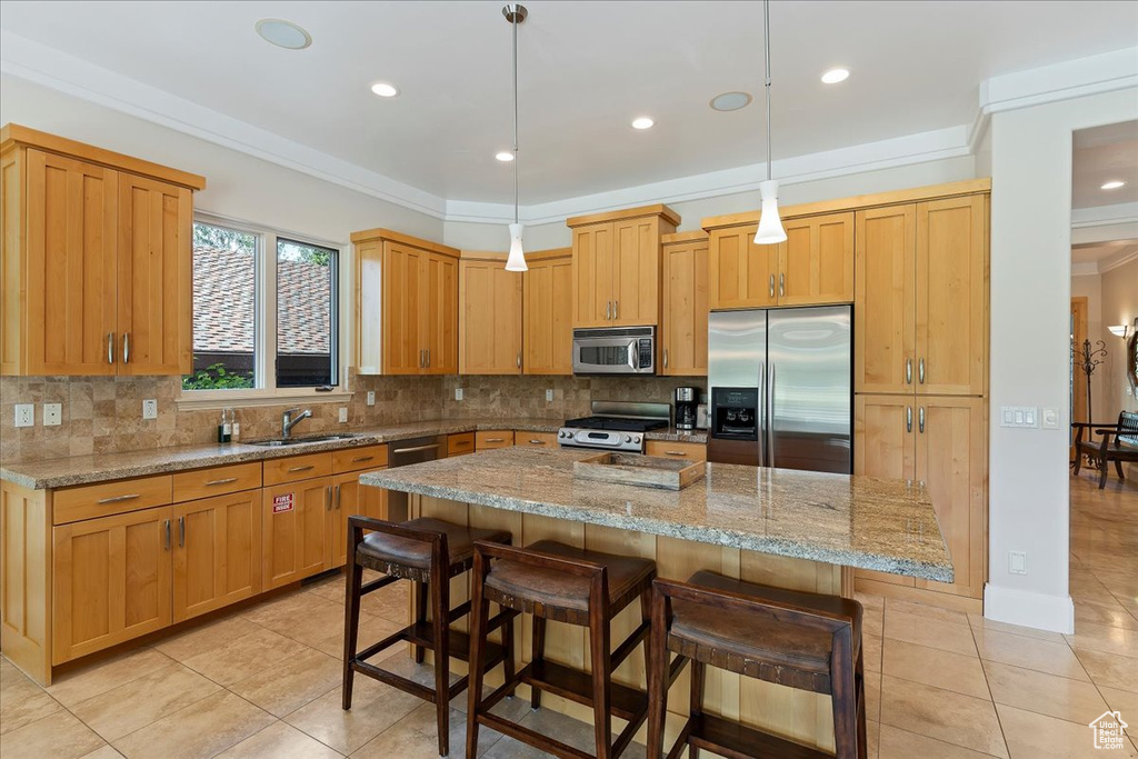 Kitchen with a kitchen island, stainless steel appliances, decorative light fixtures, backsplash, and sink