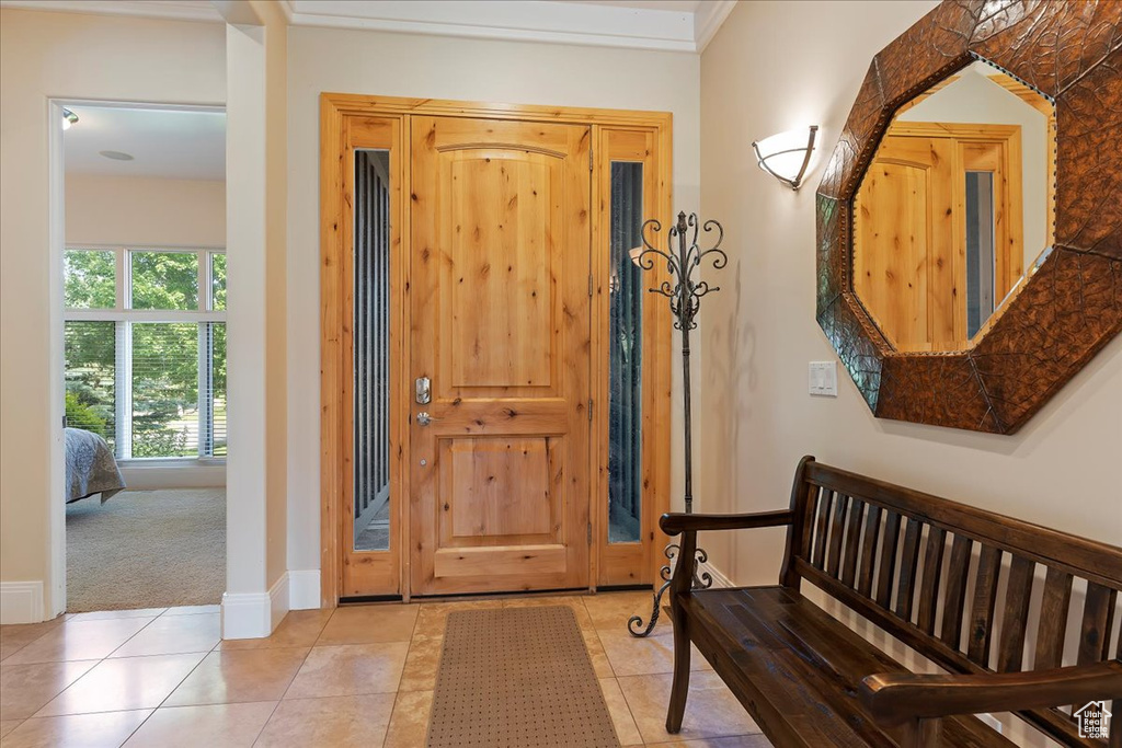 Entryway with carpet floors and crown molding