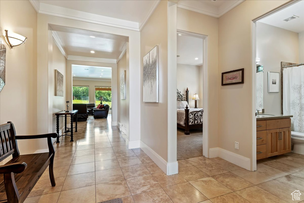 Hall with light tile floors and crown molding