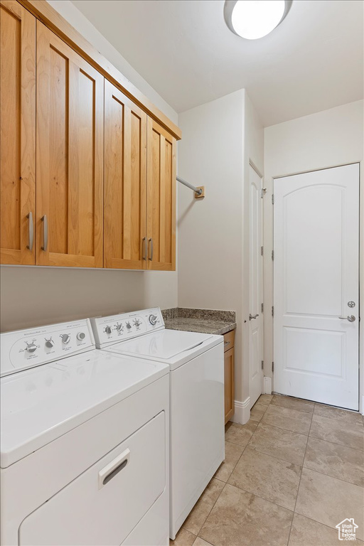 Washroom with cabinets, light tile floors, and washing machine and clothes dryer