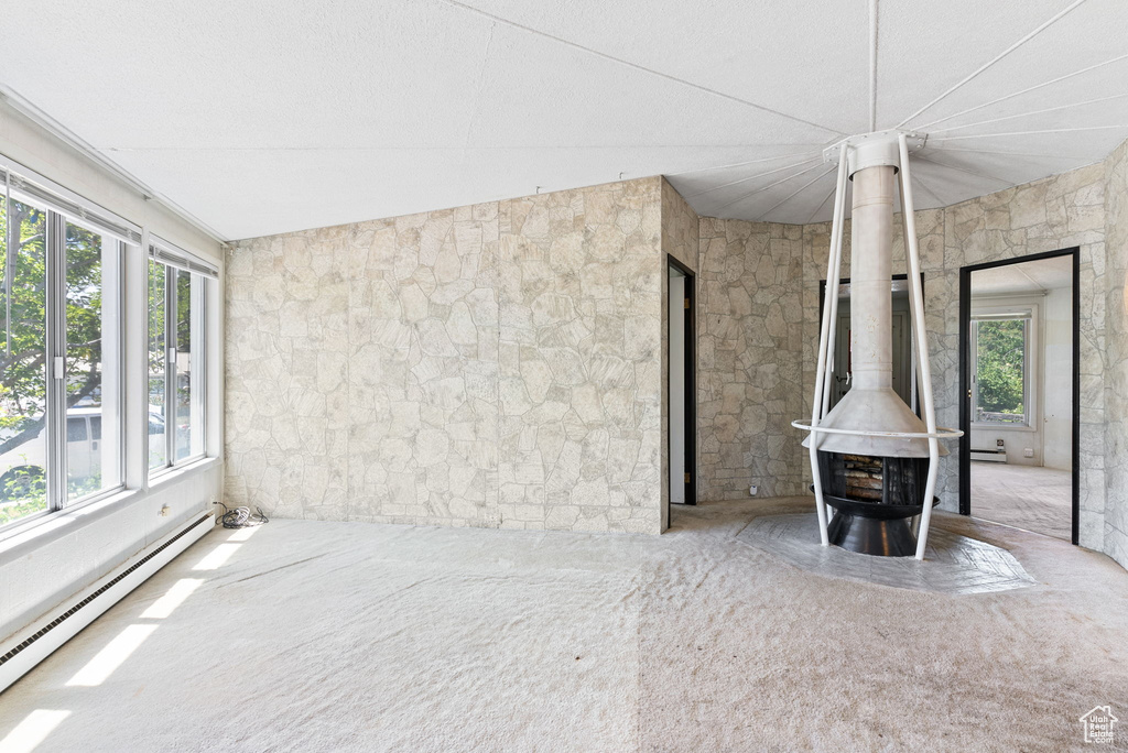 Interior space with a healthy amount of sunlight, a baseboard radiator, and a wood stove