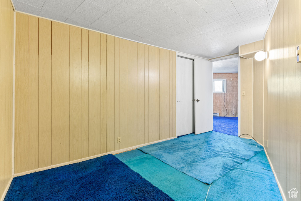 Carpeted empty room featuring wooden walls