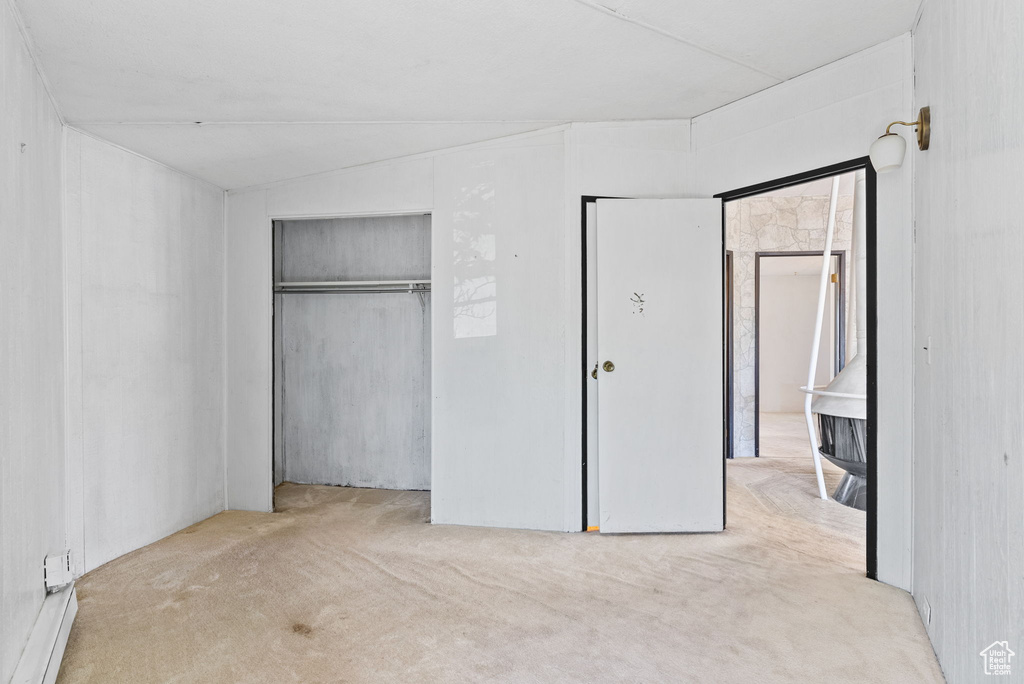 Unfurnished bedroom with a closet, vaulted ceiling, and light carpet