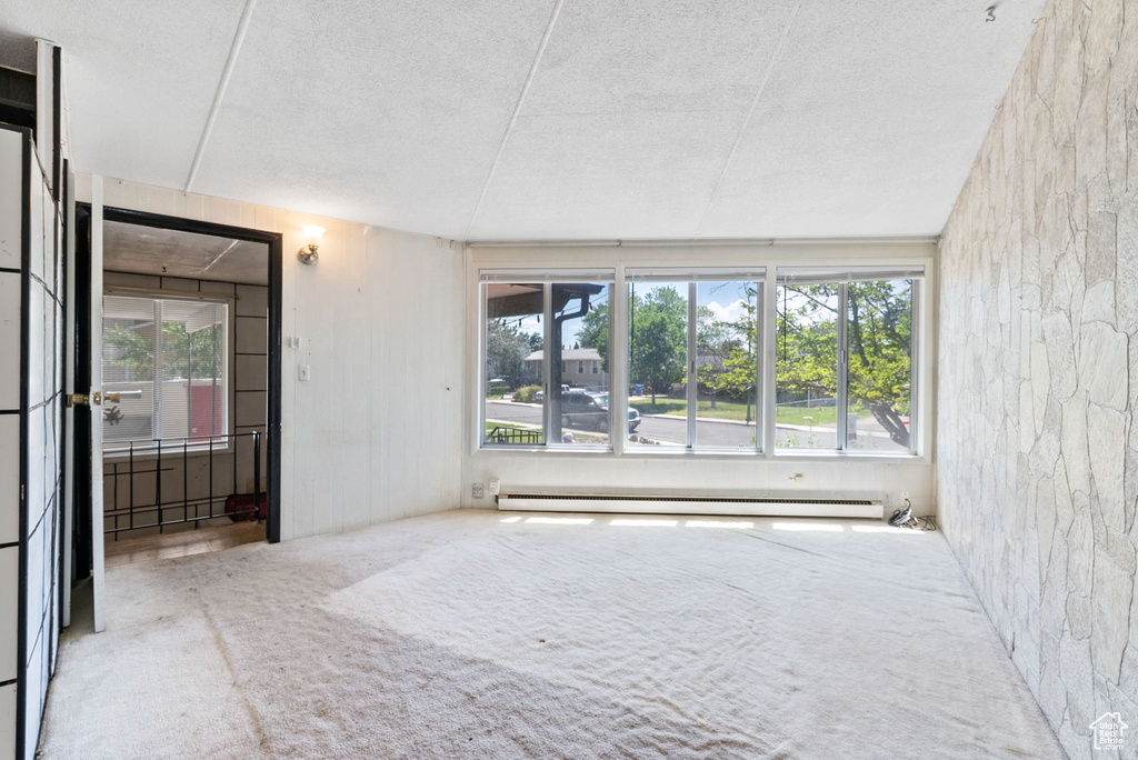 Spare room featuring a baseboard radiator, a textured ceiling, and carpet floors