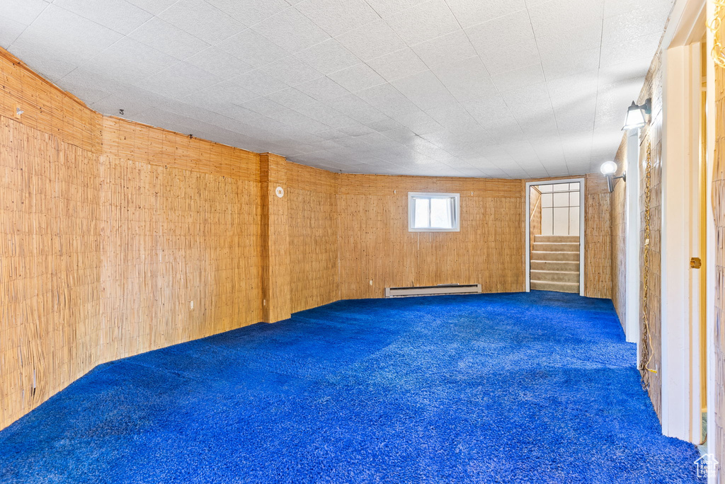 Carpeted spare room with wooden walls and baseboard heating