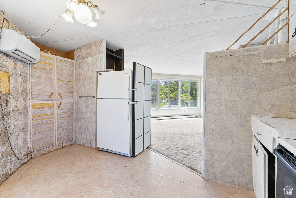 Interior space with white fridge, a wall unit AC, range, baseboard heating, and light tile floors