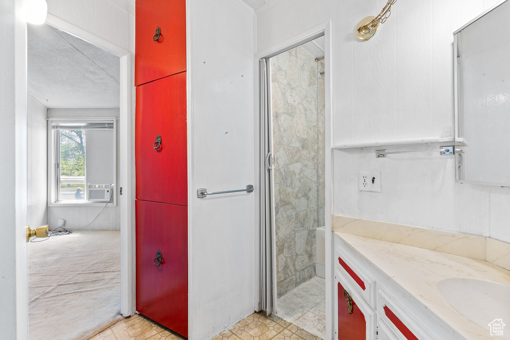 Bathroom with tile floors, a tile shower, a textured ceiling, and vanity