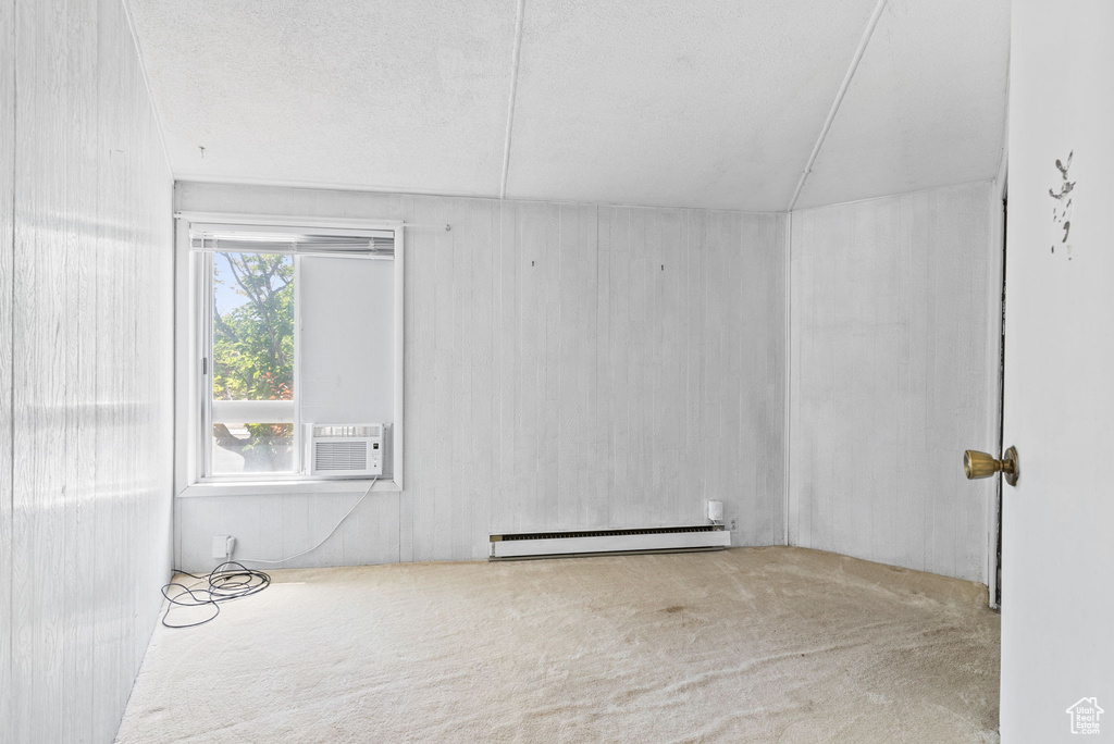 Carpeted empty room with a baseboard heating unit and a textured ceiling