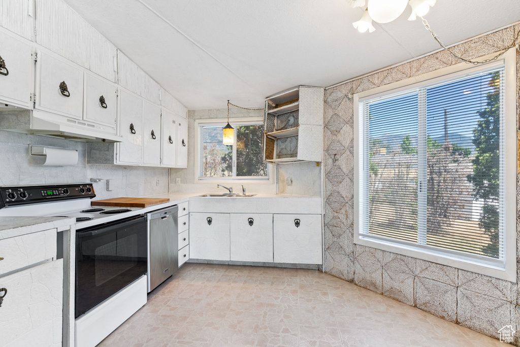 Kitchen with a healthy amount of sunlight, dishwasher, white range with electric cooktop, and decorative light fixtures