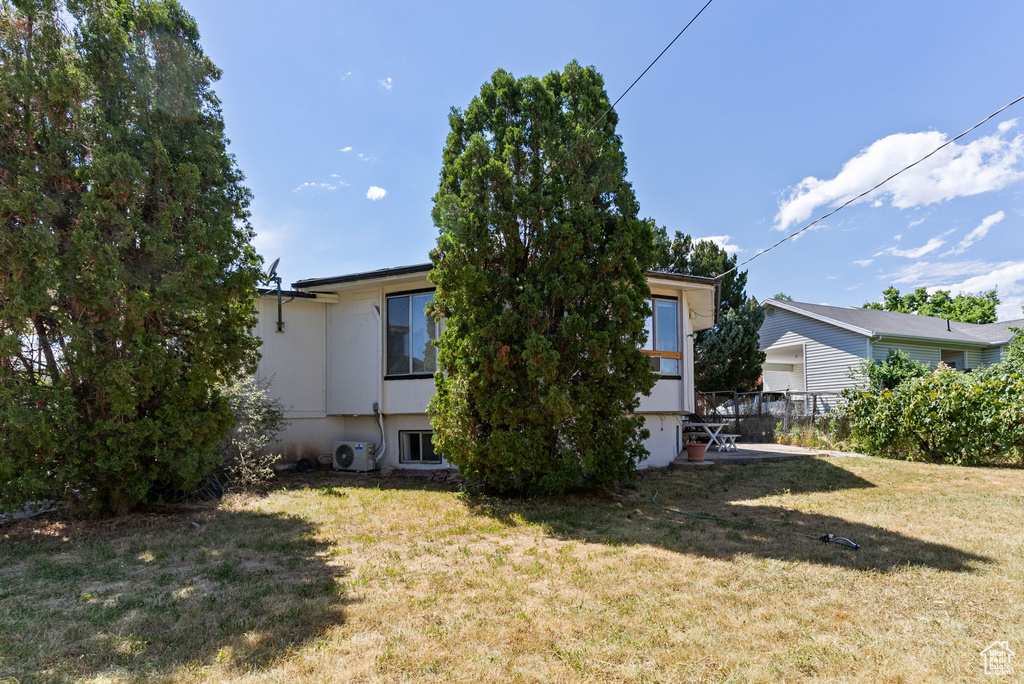 Rear view of property featuring central AC and a yard