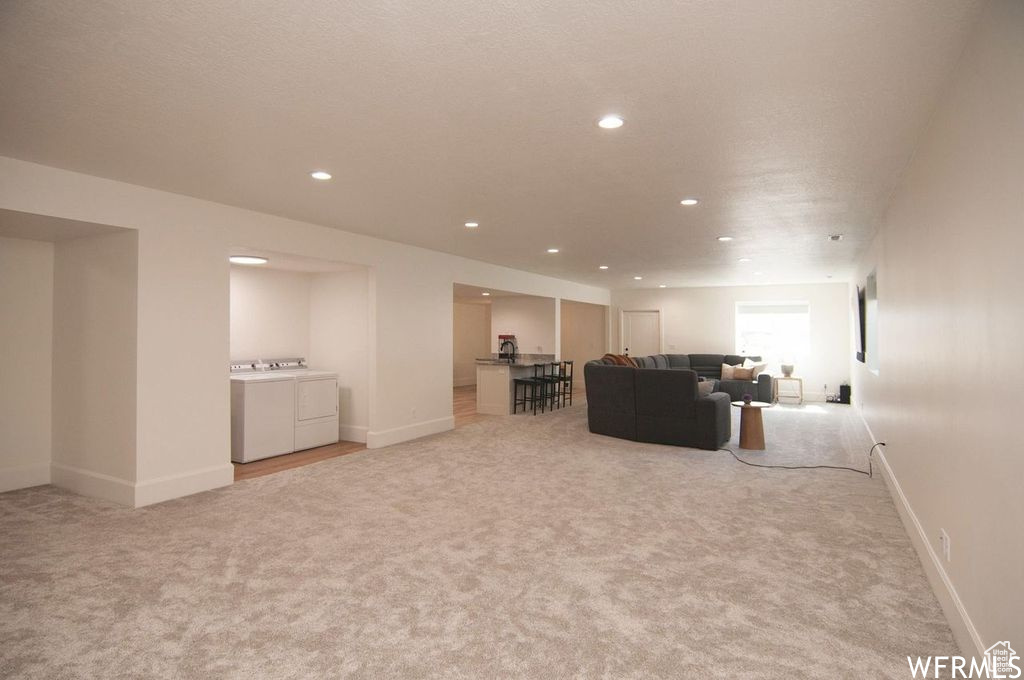 Carpeted living room with washing machine and dryer