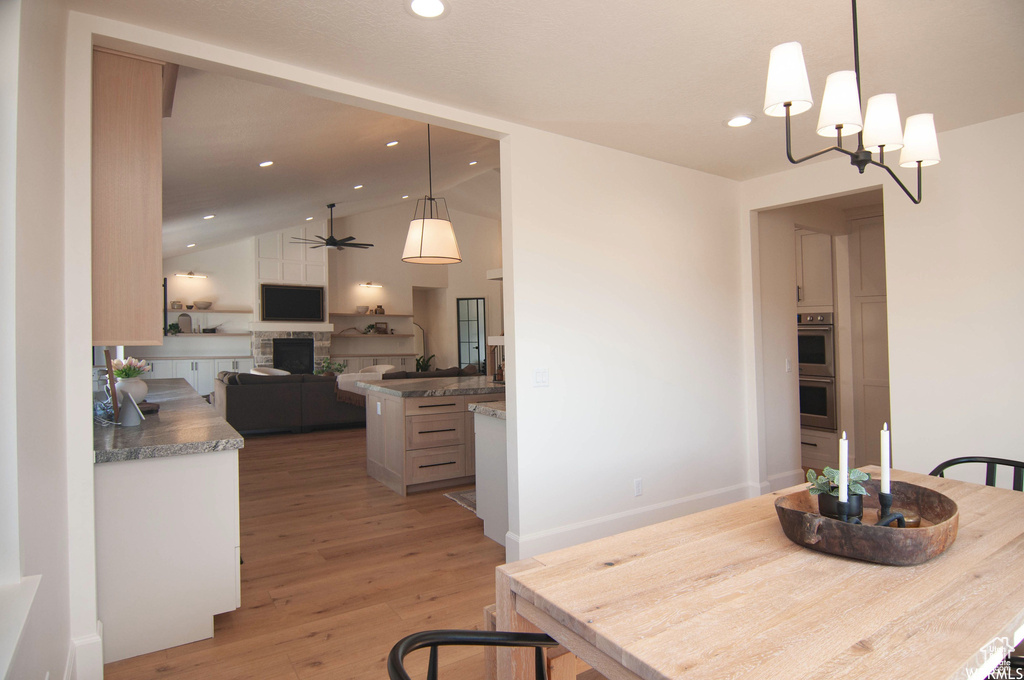 Dining area featuring vaulted ceiling, hardwood / wood-style floors, and ceiling fan with notable chandelier