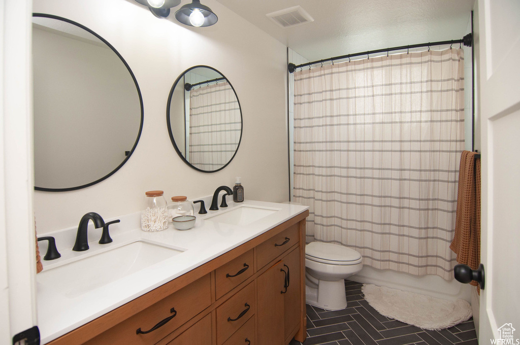 Bathroom with tile flooring, double sink, toilet, and vanity with extensive cabinet space