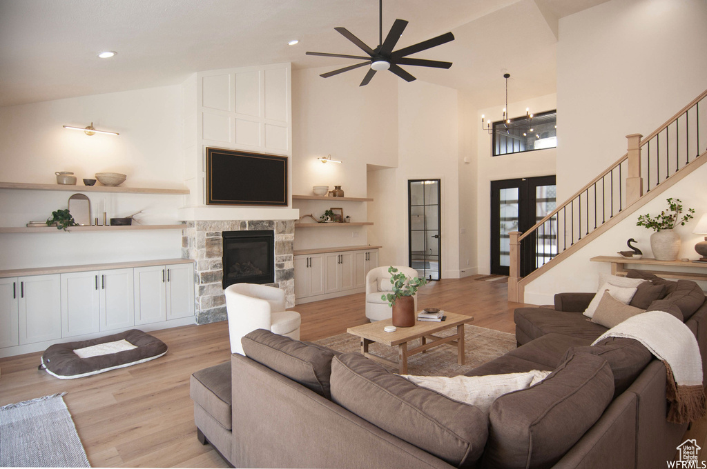 Living room with high vaulted ceiling, light hardwood / wood-style floors, a fireplace, and ceiling fan