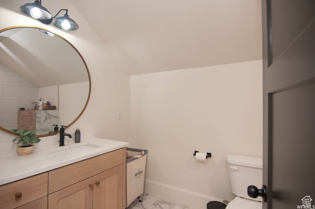 Bathroom featuring tile flooring, lofted ceiling, toilet, and vanity