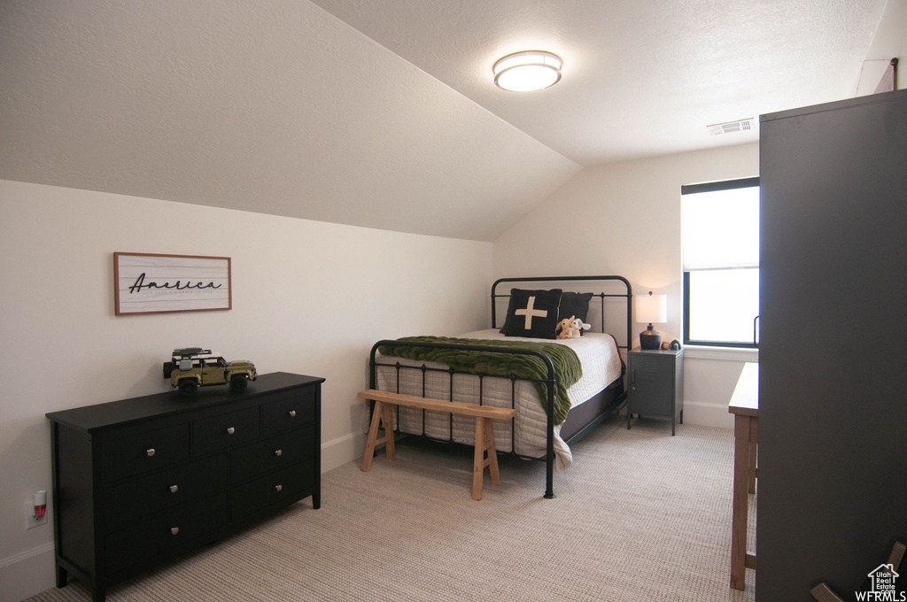 Carpeted bedroom featuring vaulted ceiling