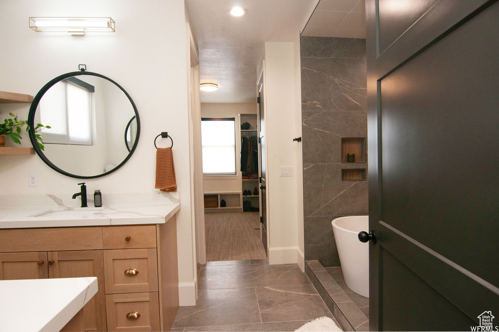 Bathroom with tile walls, tile floors, vanity, and a bathing tub