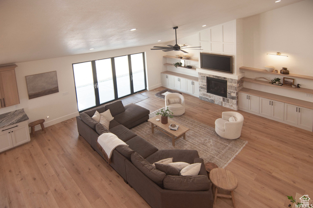 Living room with vaulted ceiling, ceiling fan, light hardwood / wood-style flooring, and a fireplace