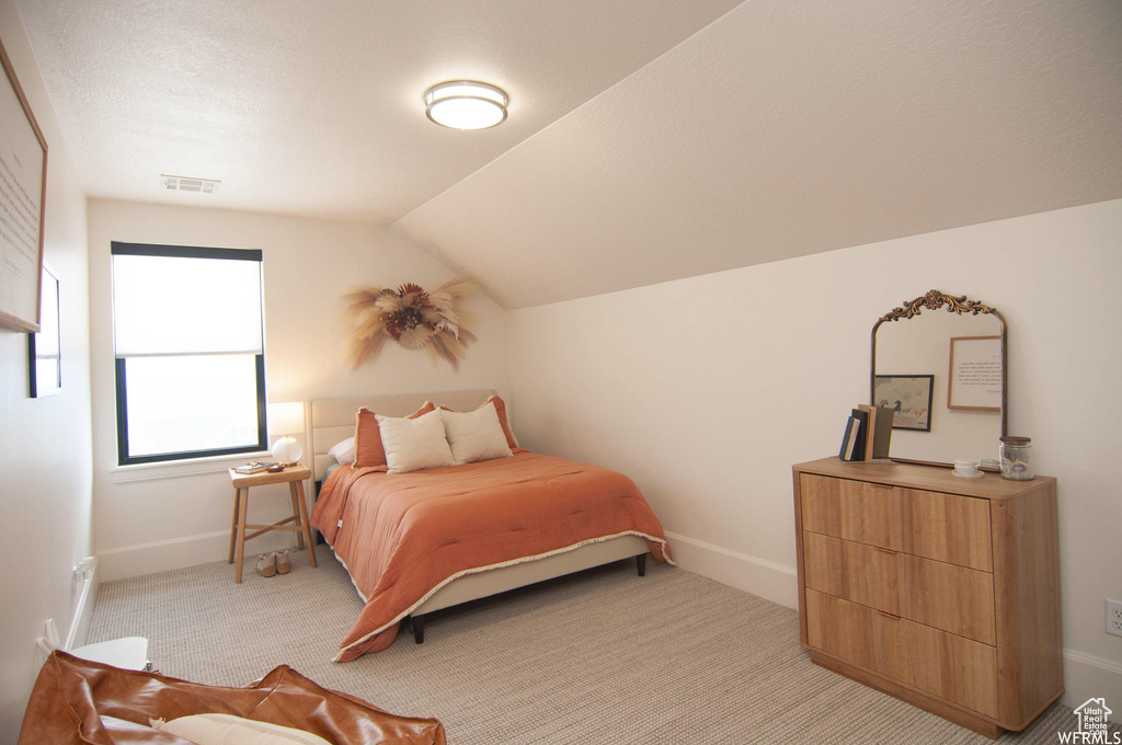 Bedroom featuring lofted ceiling and light colored carpet