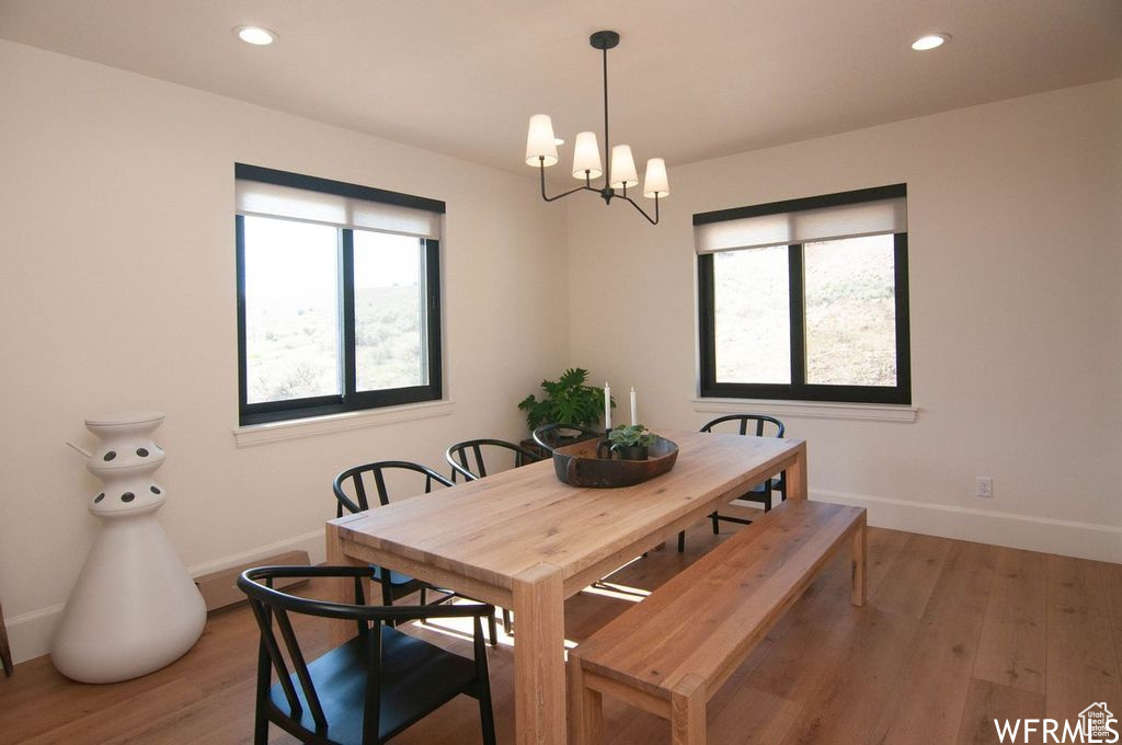 Dining area featuring a healthy amount of sunlight, wood-type flooring, and a chandelier