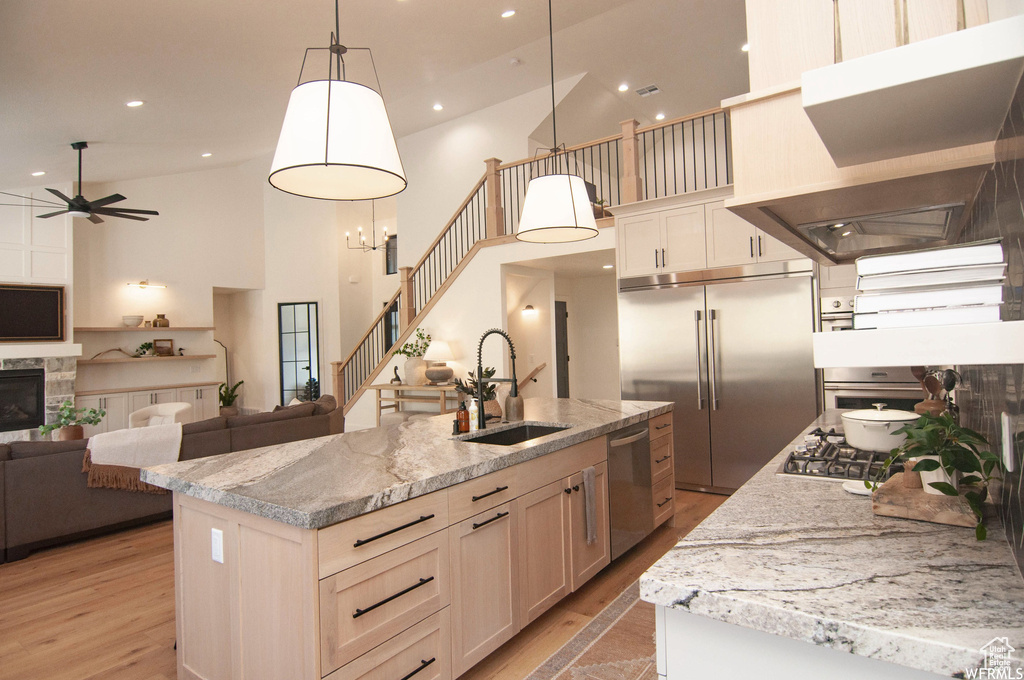 Kitchen featuring high vaulted ceiling, a kitchen island with sink, light hardwood / wood-style floors, and stainless steel appliances