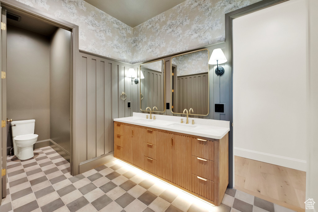 Bathroom featuring double vanity, tile patterned floors, baseboards, and toilet