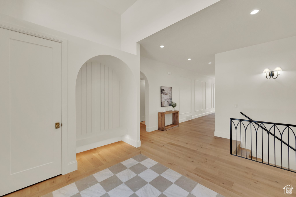 Corridor featuring light wood finished floors, recessed lighting, arched walkways, and baseboards