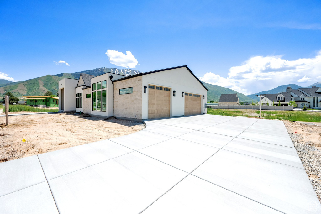 View of front facade with a mountain view, a garage, a residential view, and driveway
