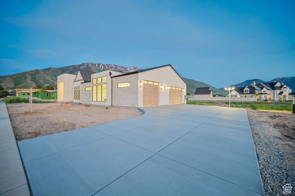 View of front of house featuring a mountain view, concrete driveway, a garage, and a residential view
