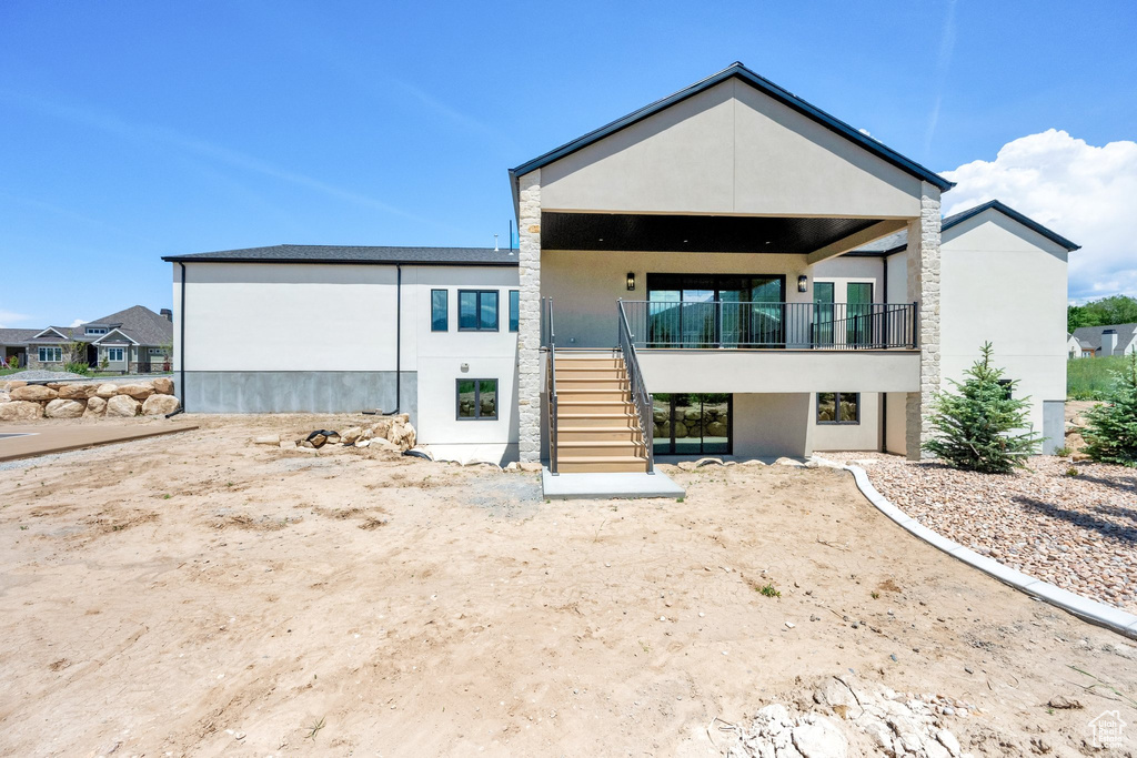 Rear view of house featuring stairway and stucco siding