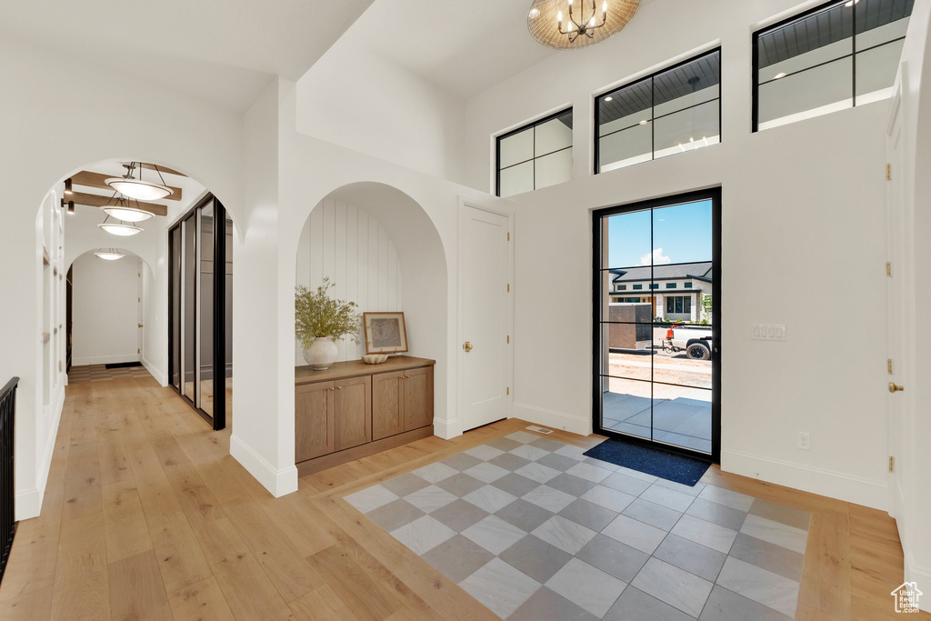 Foyer entrance featuring arched walkways, light wood finished floors, a high ceiling, and baseboards