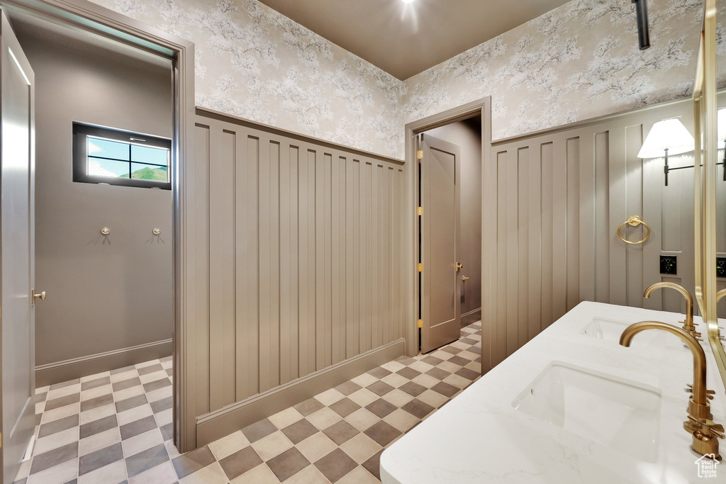 Bathroom featuring tile patterned floors, a wainscoted wall, double vanity, and a decorative wall