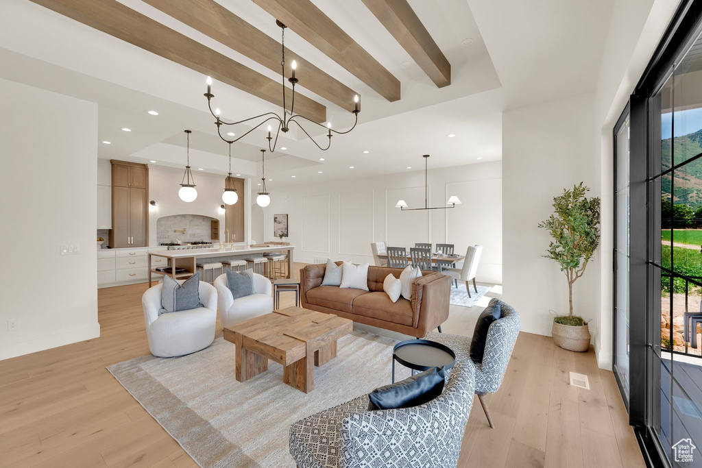 Living area featuring light wood finished floors, beam ceiling, a chandelier, and recessed lighting