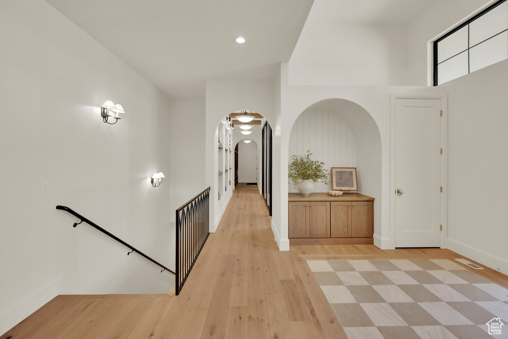 Entryway with arched walkways, light wood-style flooring, baseboards, and recessed lighting