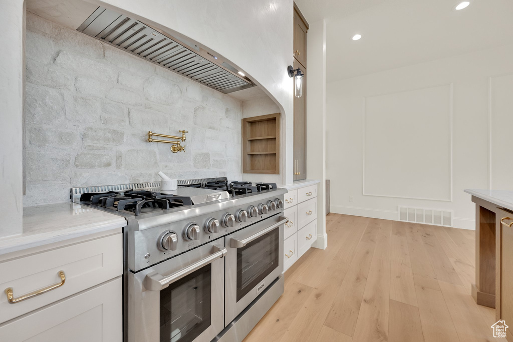 Kitchen featuring range with two ovens, light countertops, custom range hood, recessed lighting, and decorative backsplash