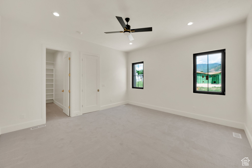 Unfurnished bedroom with light carpet, multiple windows, recessed lighting, a spacious closet, and baseboards